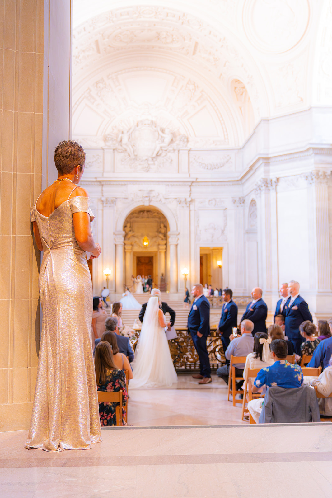 Wedding guest watching a ceremony from the back inside San Francisco City Hall