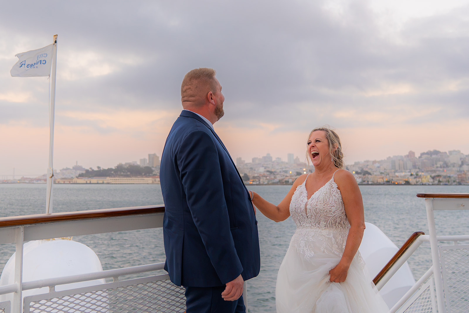 Cinematic photo of a bride laughing with the groom on the deck of a San Francisco sunset wedding cruise