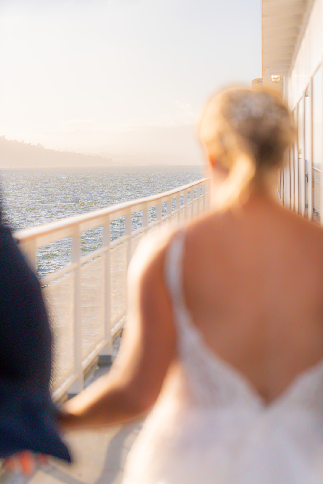 Bride and groom walking together along the side of a boat during their San Francisco wedding cruise