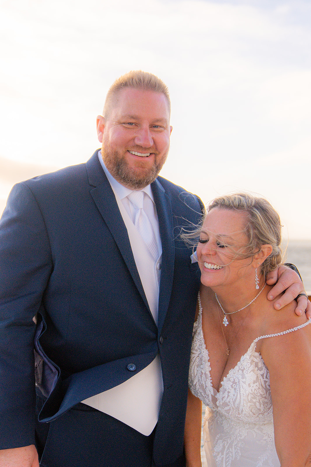 Bride and groom standing together in the wind on the deck of a San Francisco wedding cruise