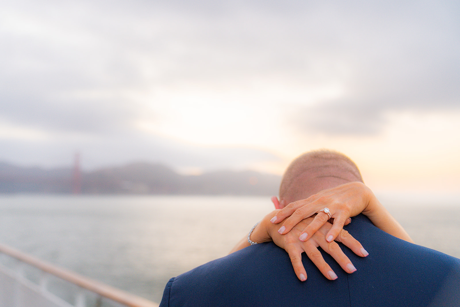Bride with her hands around the groom’s neck showing her wedding ring on the deck of a San Francisco sunset dinner cruise
