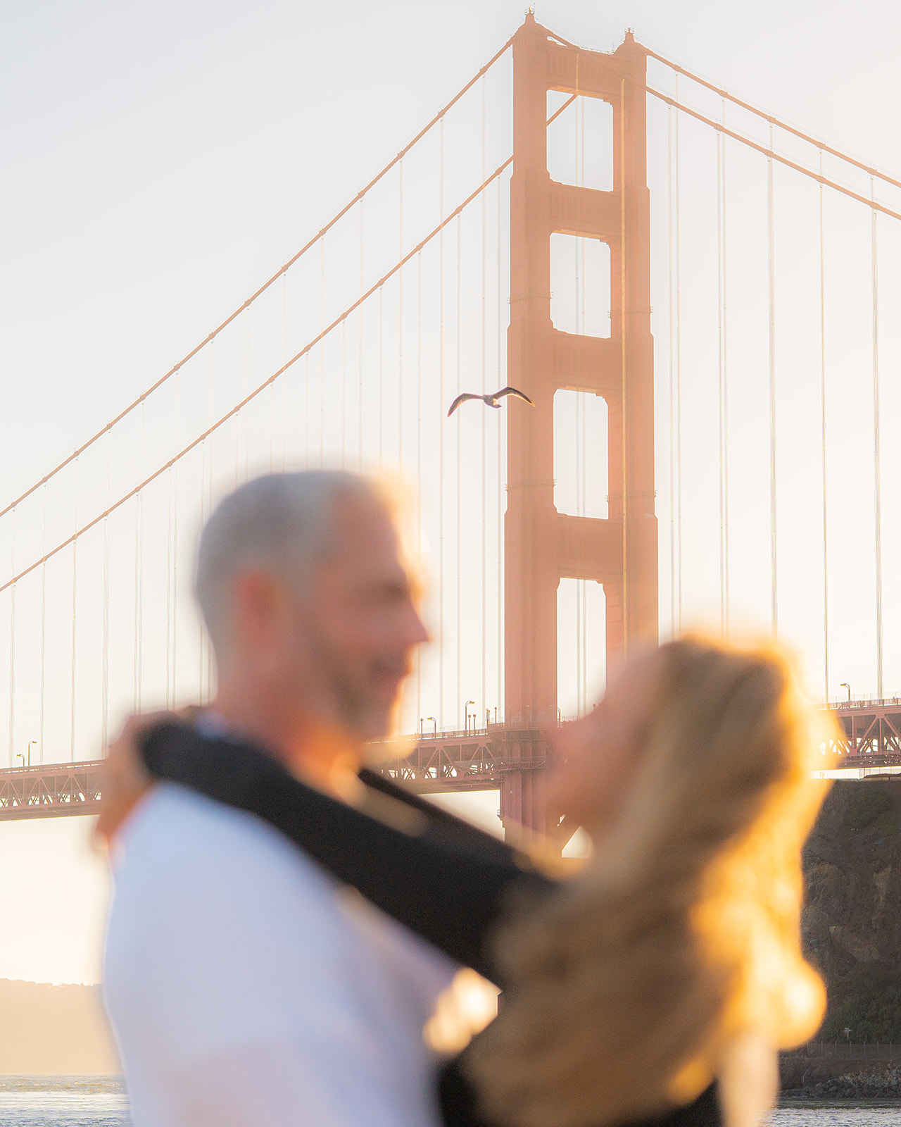 Seagull near a couple at sunset by the San Francisco Bay with the Golden Gate Bridge in the background