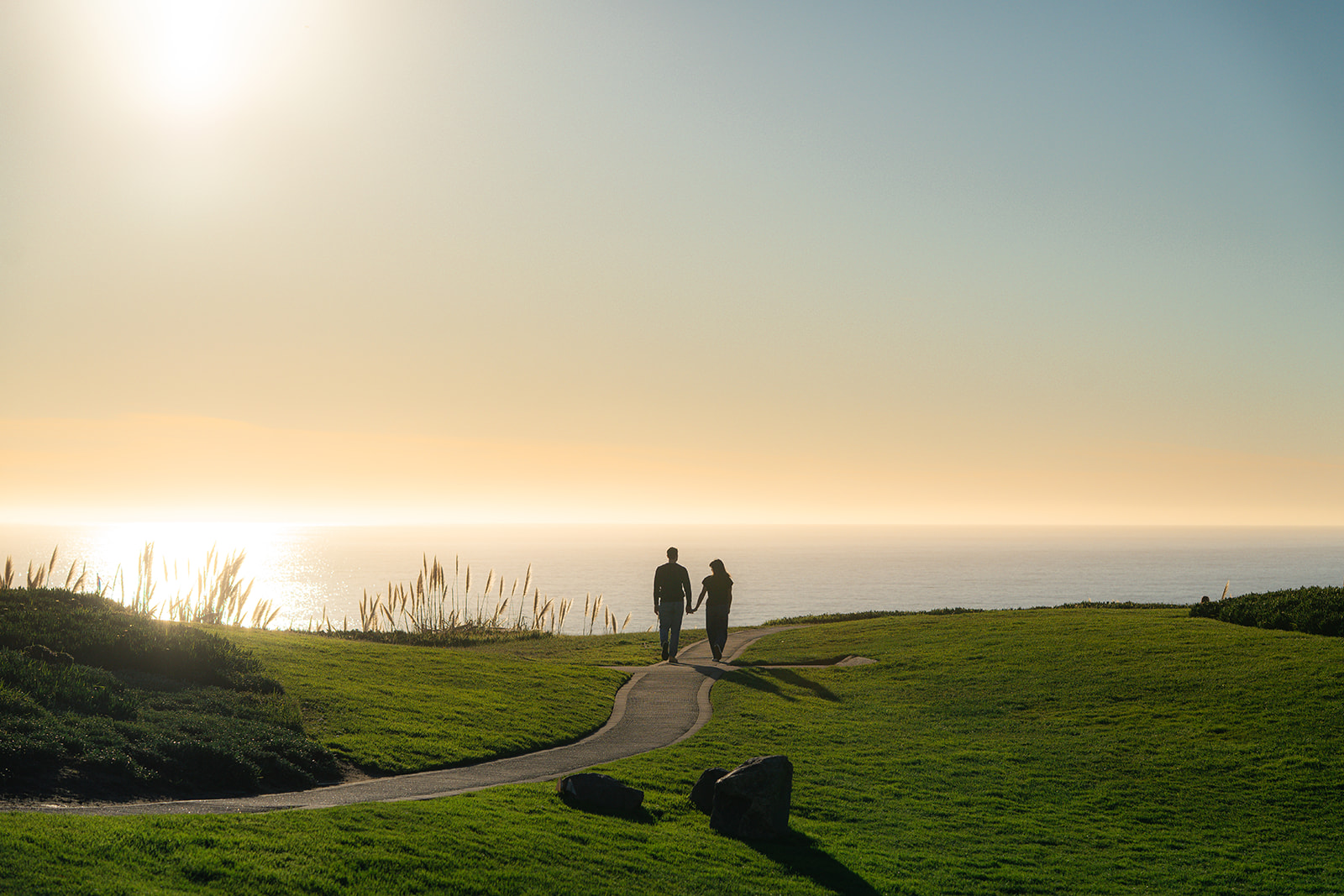 Couple walking along a pathway at Seascape Beach Resort in Aptos during sunset.
