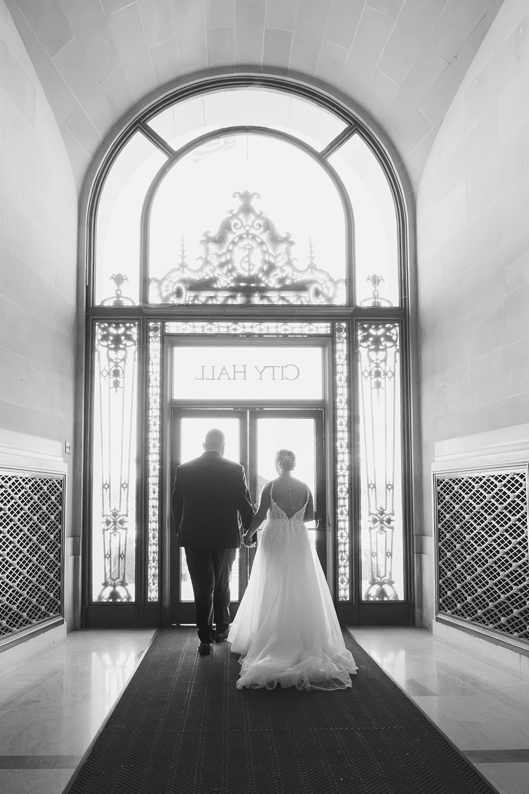 Newlywed couple exiting through the doors of San Francisco City Hall after their wedding ceremony