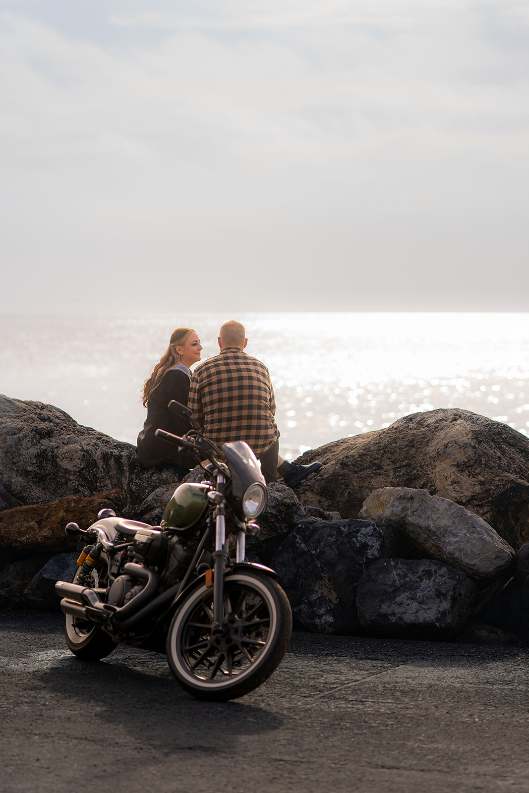 Couple with a motorcycle beside the sparkling ocean at Pacifica State Beach in California