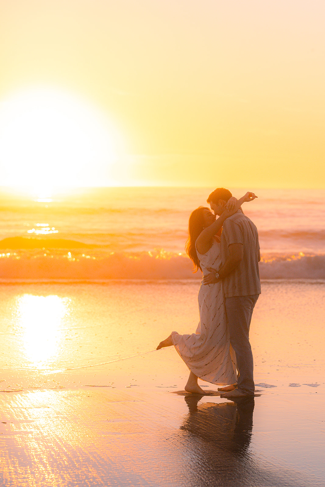 Couple dancing barefoot on the sand at sunset on a beach in Santa Cruz.