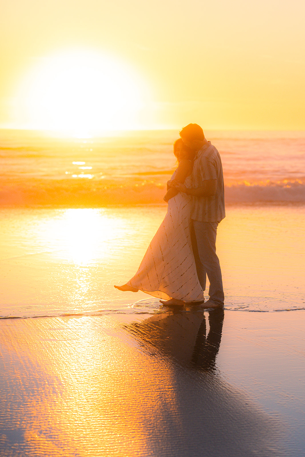 Couple embracing barefoot on the sand at sunset on a beach in Santa Cruz.