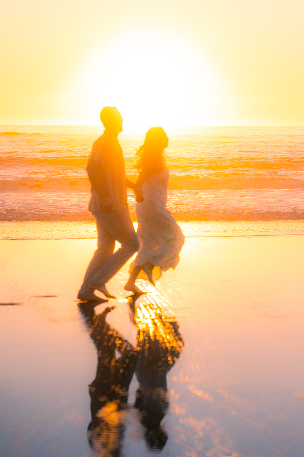 Couple running barefoot on the sand at sunset on a beach in Santa Cruz.