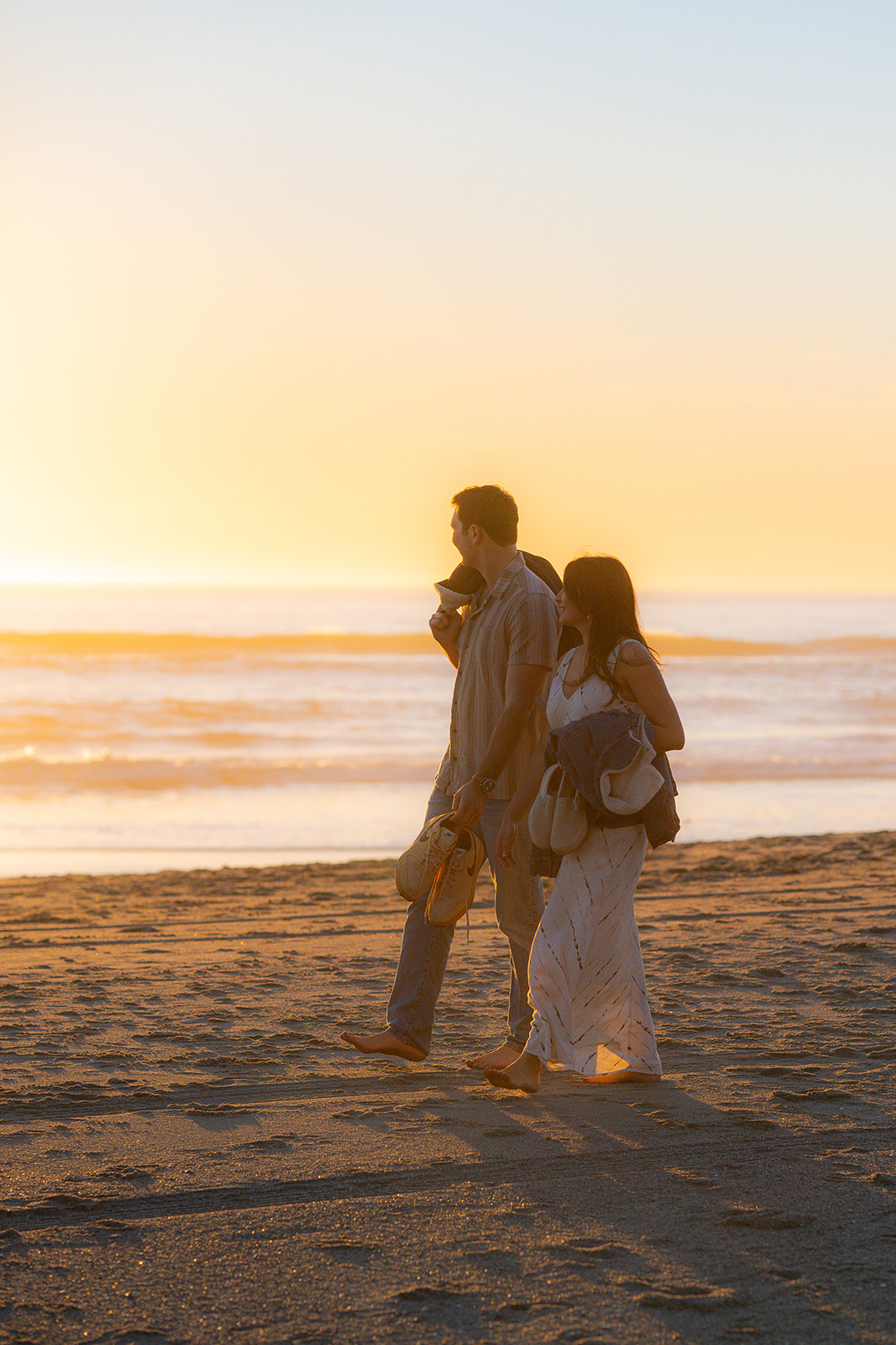 Couple walking barefoot along the sand at sunset on a beach in Santa Cruz.