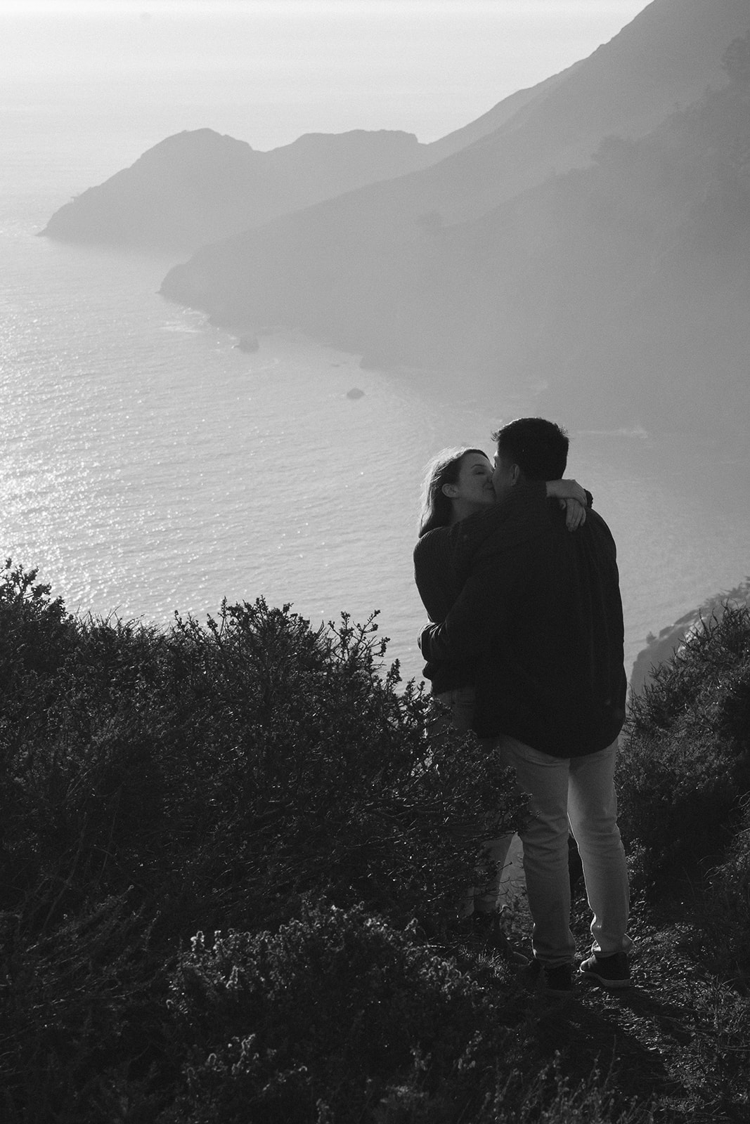 Couple on a cliffside overlooking the ocean at sunset in San Francisco.