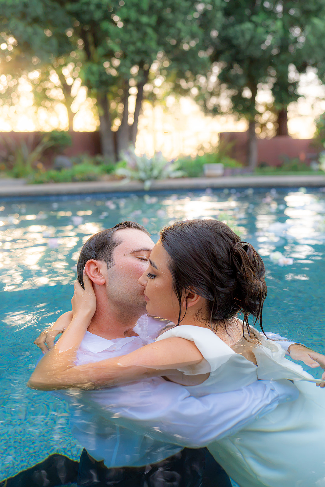 Bride and groom kissing in a pool at sunset at Rainbow Oaks Ranch in Sanger, California.