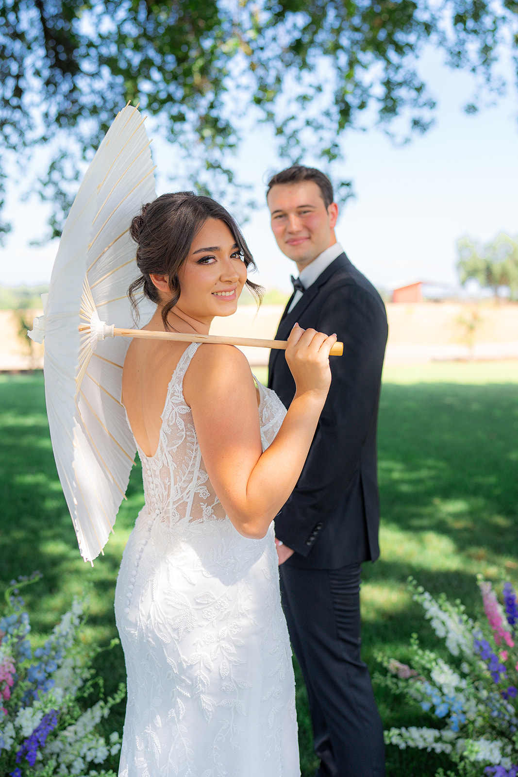 Bride and groom posing together with a parasol at Rainbow Oaks Ranch in Sanger, California.